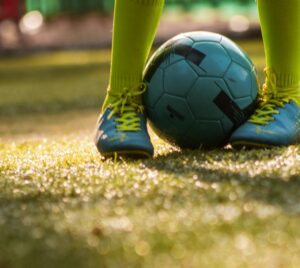 Child playing football on a lawn