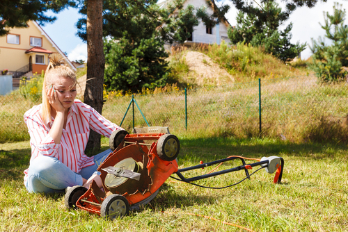 Girl sits on lawn with broken mower