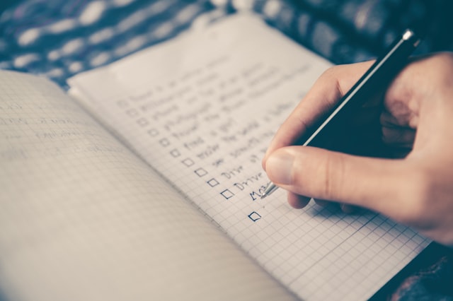 A person writing a gardening checklist in a notebook