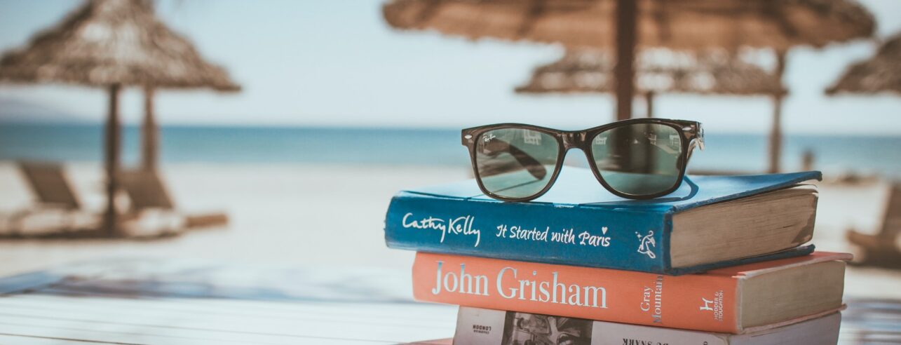 A pile of books ready for reading on the beach