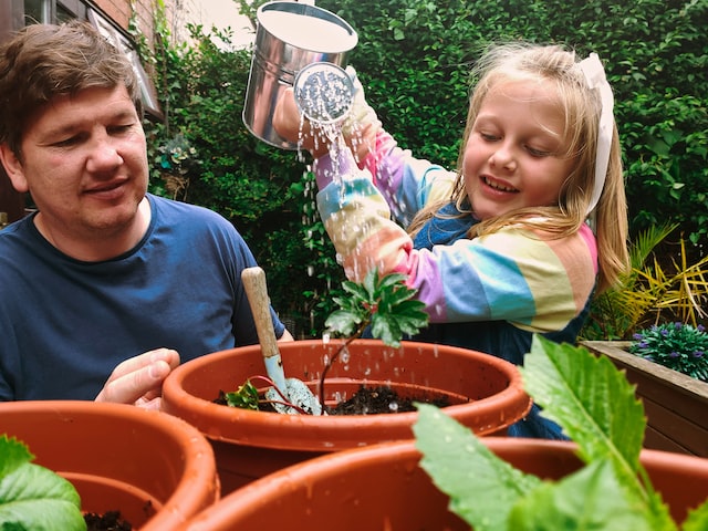 A father and daughter tending to potted plants