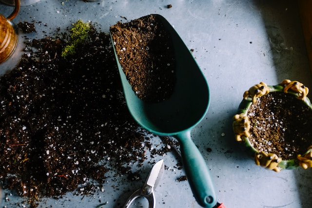 A trowel full of compost, filling a pot.