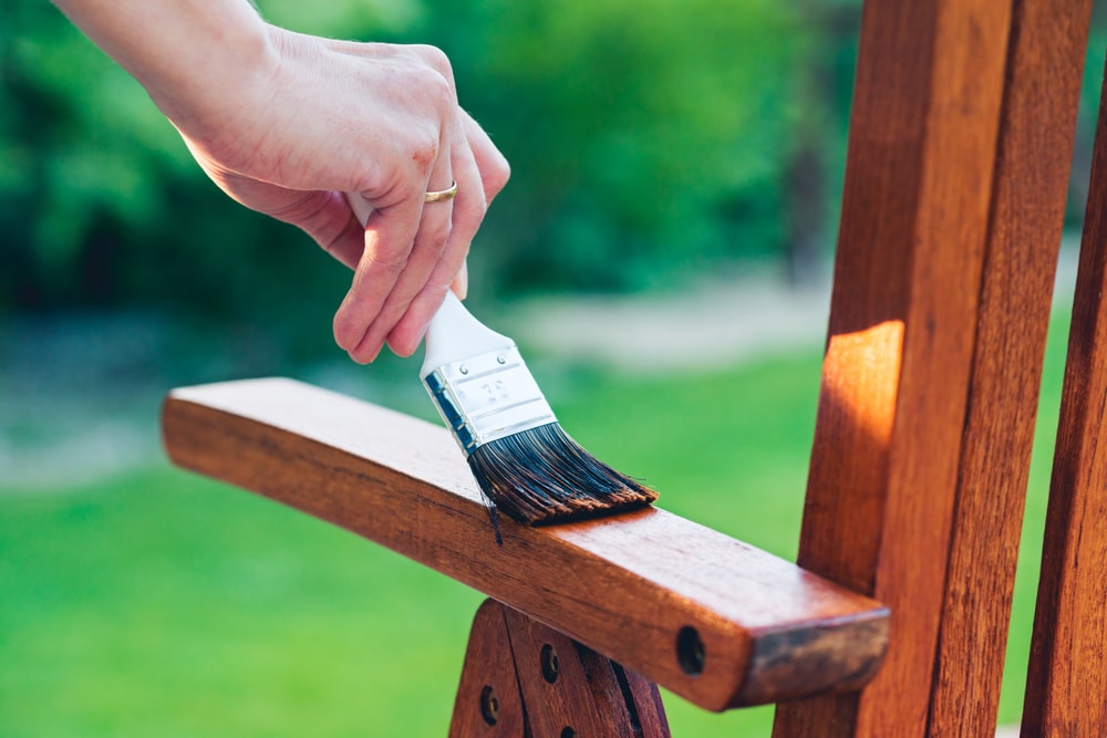 A man varnishing a garden chair. 