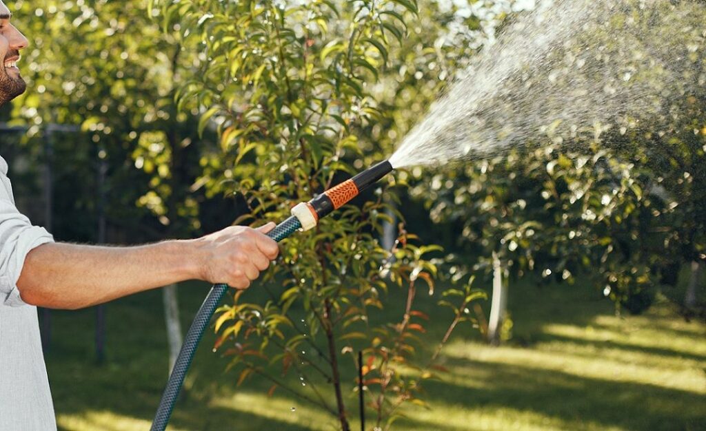 Man holding garden hose and spraying water
