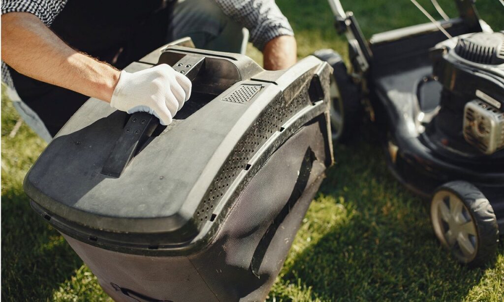 Someone emptying the grass collector box on a mower