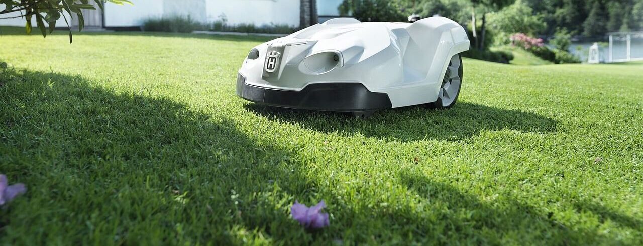 White car-like robot lawnmower on grass