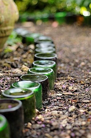 Glass bottle border between a flowerbed and a woodchip path