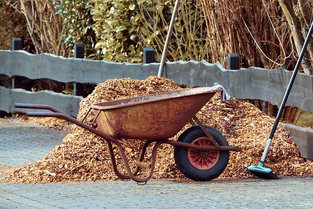 A wheelbarrow and a pile of woodchips for mulching