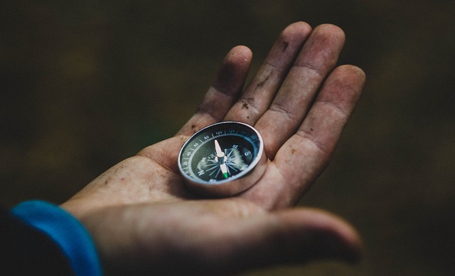 A person with a dirty hand, holding a compass in their palm