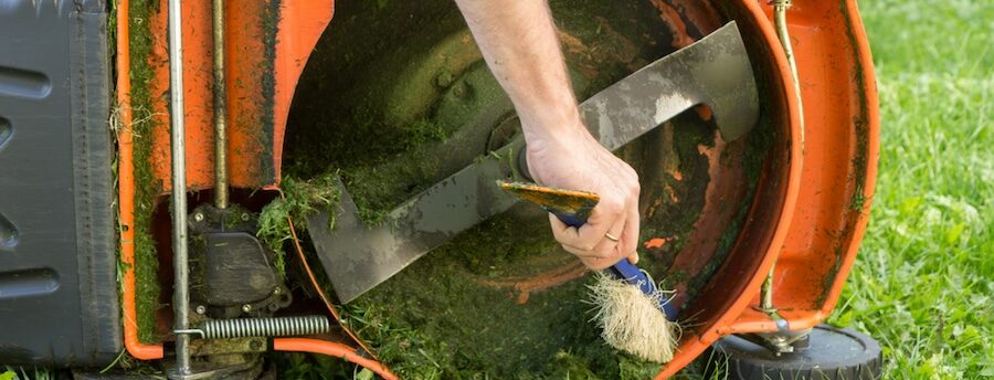 Cleaning the underside of a mower with a stiff brush