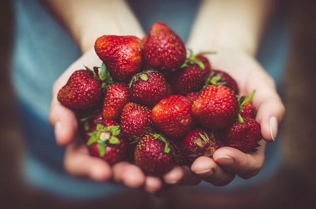 Hands holding up strawberry harvest