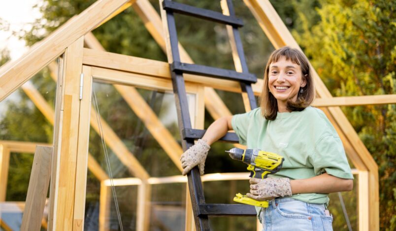 Woman constructing a DIY greenhouse